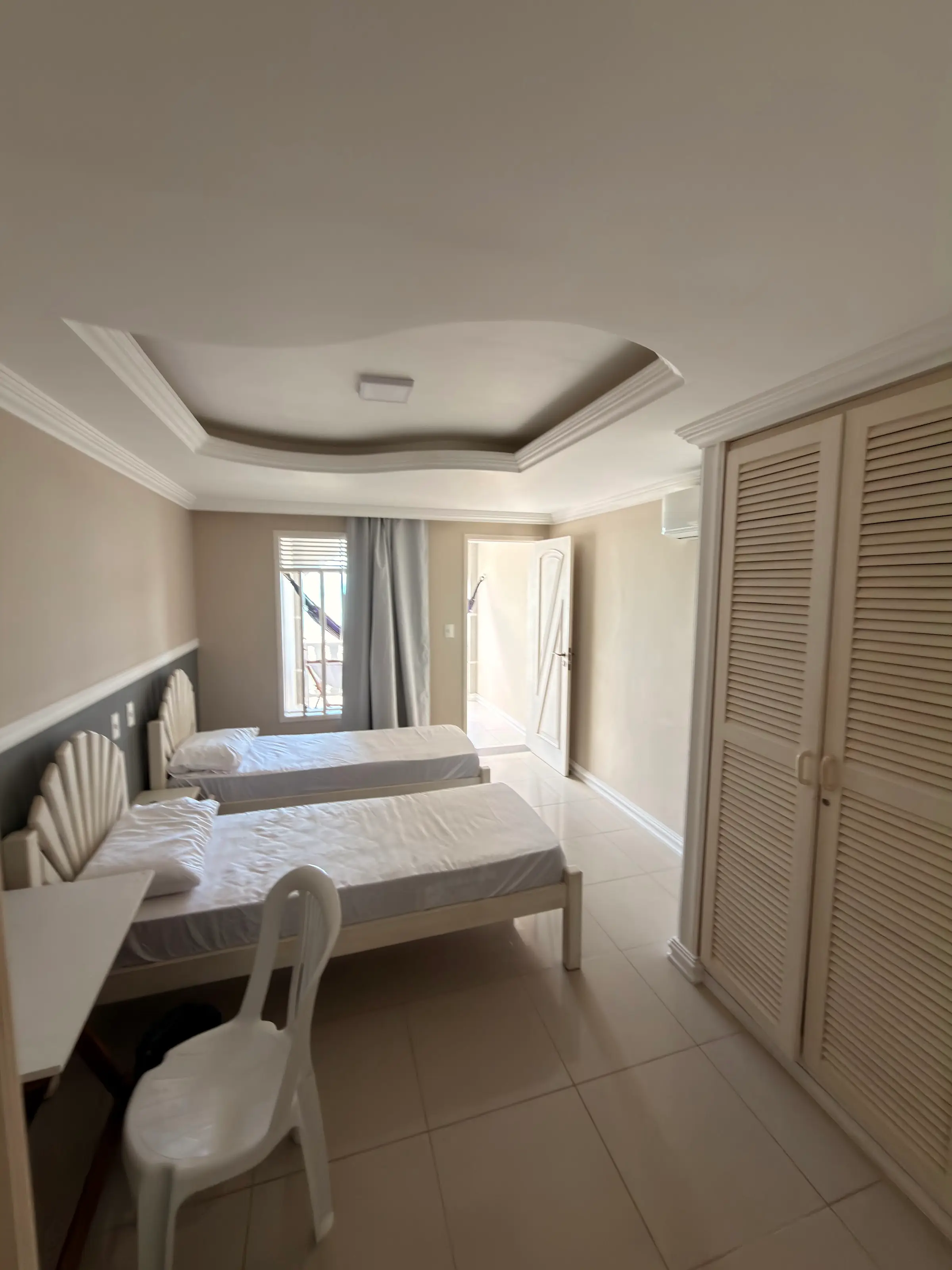 Quarto com duas camas de solteiro e escrivaninha